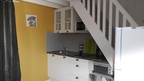 A compact kitchen with white cabinets, a microwave, and a sink.