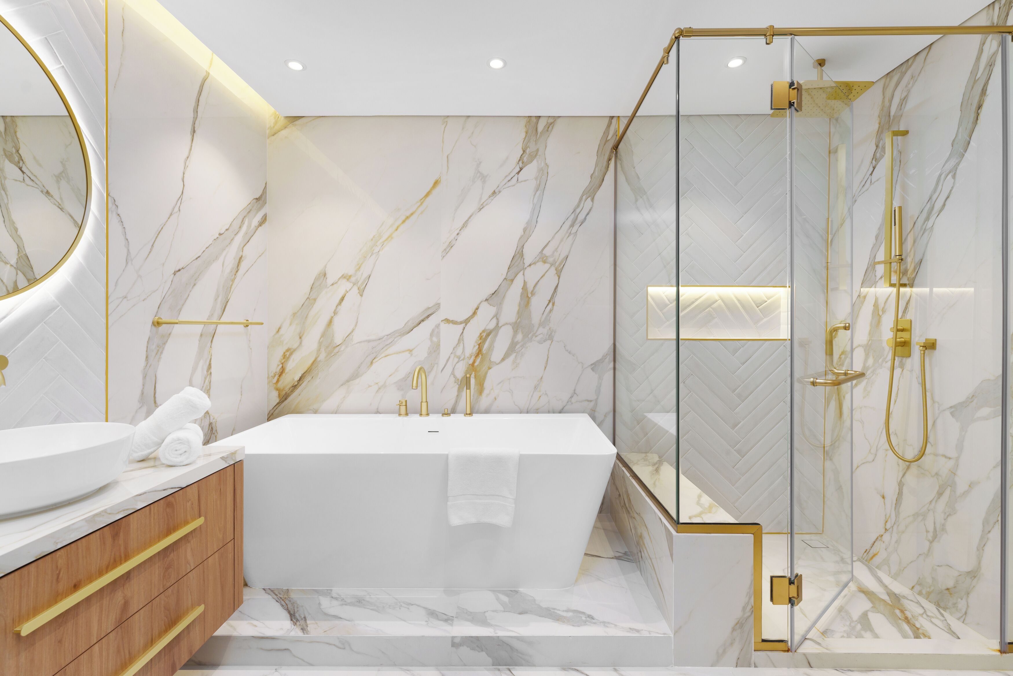 Une salle de bain moderne avec une baignoire sur pieds, une douche à parois de verre et des murs en marbre.