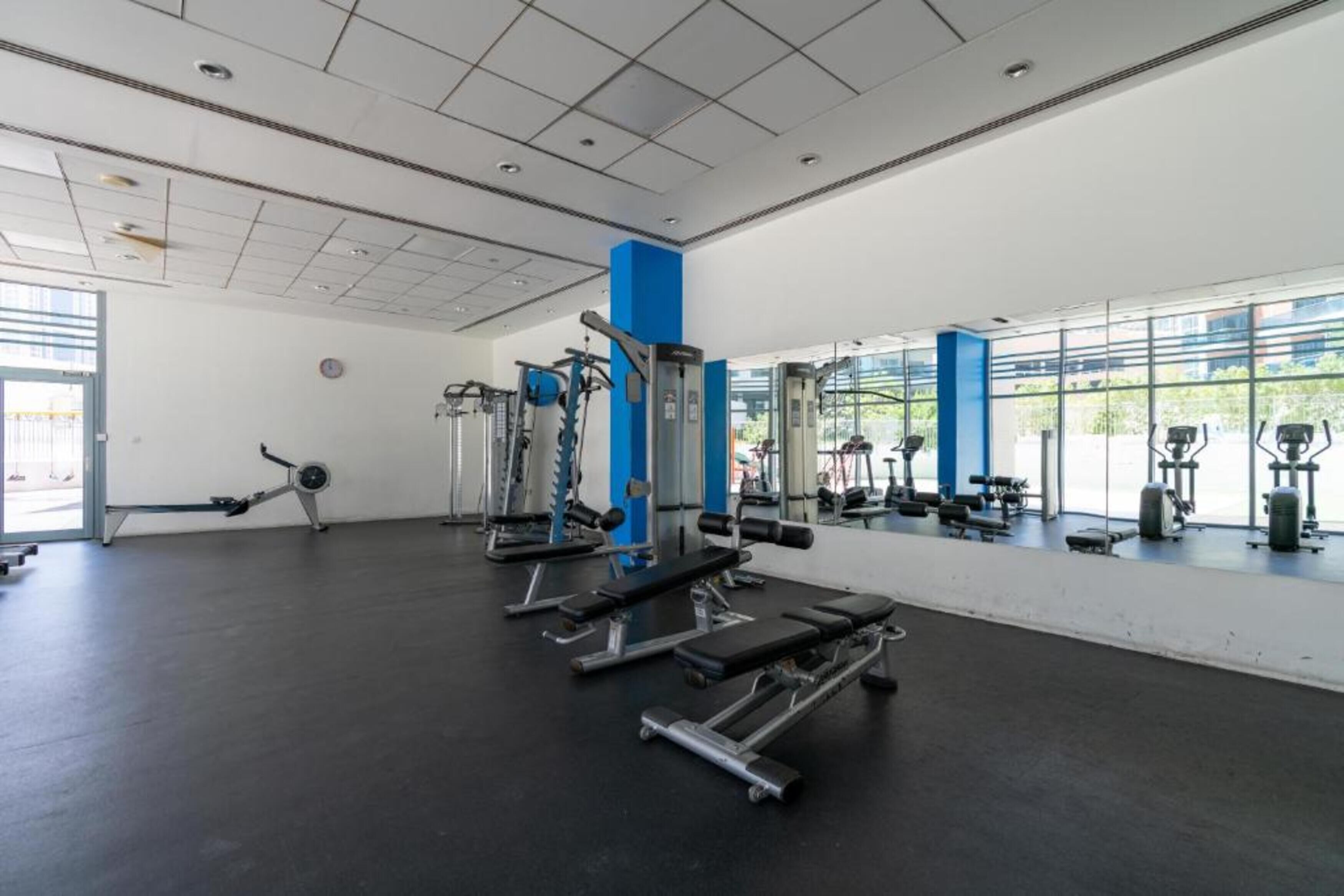Una palestra con diverse attrezzature per esercizi, ampie finestre e un design moderno e pulito.