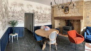 A dining area with a round table, chairs, a vase of flowers, a fireplace, and a mural on the wall.