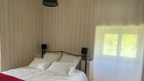 A bed with white bedding, a red blanket, and two bedside lamps.