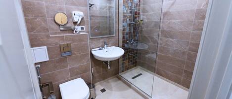 Un baño moderno con inodoro, lavamanos y ducha envuelta en vidrio.