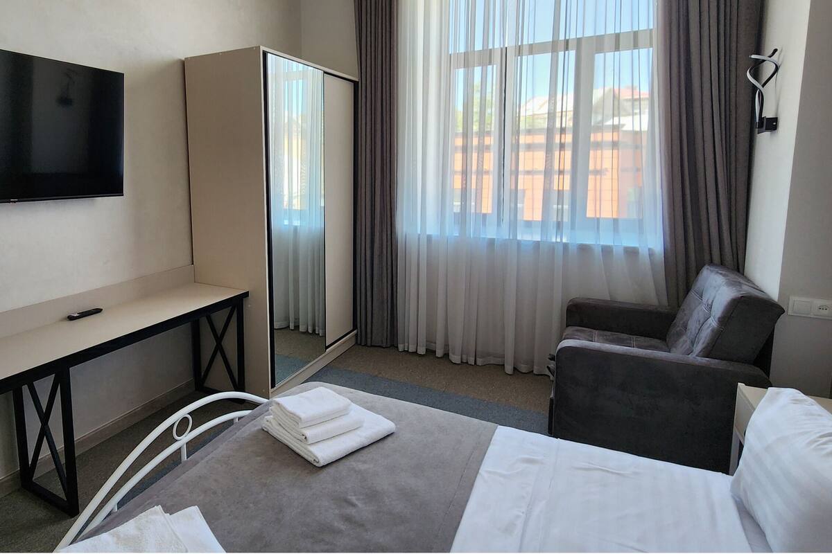 Une chambre d’hôtel comprenant un lit, un bureau, une chaise, une télévision et une armoire.