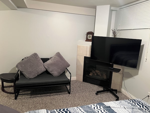 A room with a black sofa, a flat-screen TV, and a fireplace.