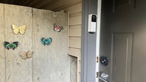 A concrete wall with butterfly decorations and a door with a security keypad.