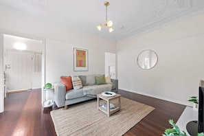 A living room with a grey sofa, a small coffee table, a round mirror, and a painting on the wall.