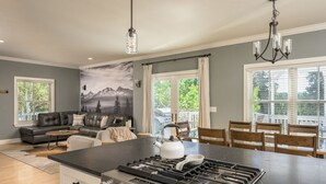 Una cocina moderna con una isla central, un comedor con vistas y una sala de estar con un cuadro grande.