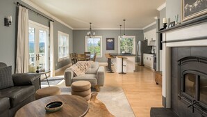 Una sala de estar moderna con chimenea, una zona de comedor y una cocina con taburetes de bar.