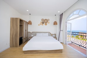 Un dormitorio con una cama grande, un armario de madera y un balcón con vistas al mar.
