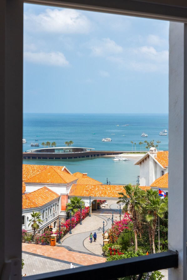 Une vue sur la côte, avec un port de plaisance, des bâtiments aux toits recouverts de tuiles orange et un chemin piétonnier.
