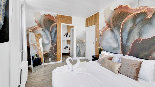 Una camera d'albergo moderna con un ampio letto, un armadio e uno specchio.