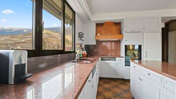 A kitchen with a large window, a built-in espresso machine, and a view of the countryside.