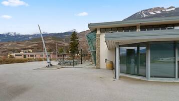 A modern building with a large glass facade, a wind turbine in the background, and a mountainous landscape.