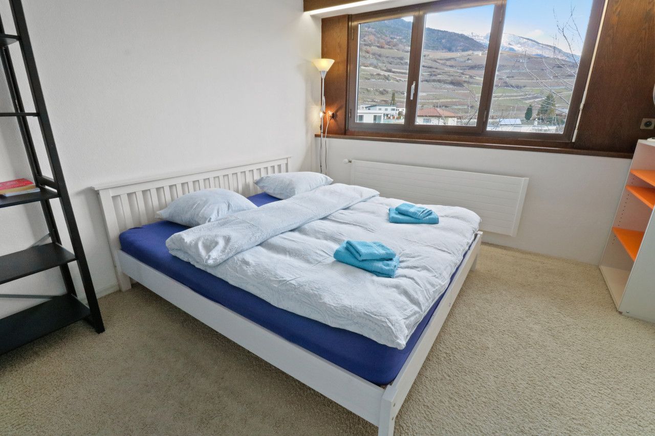 Una camera da letto con un letto, un termosifone, una finestra vista e una libreria.