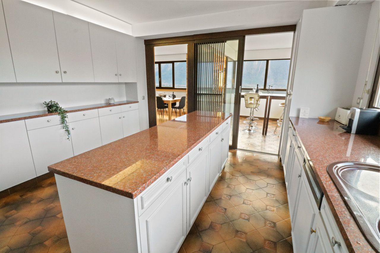 A modern kitchen with white cabinets, granite countertops, and a view to a dining area.