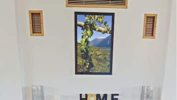 Ein Kamin mit einem darüber hängenden Bild, einem Sims mit der Aufschrift 'HOME' und je einem Korb auf jeder Seite des Kamins.