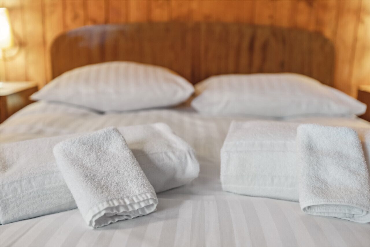 Ein Bett mit weißen Kissen und gefalteten weißen Handtüchern.