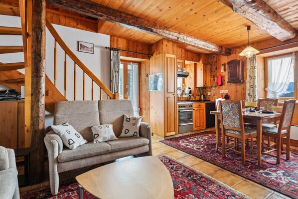 A cozy wooden interior with a sofa, dining table, and kitchen area.