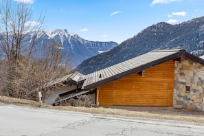 A mountain cabin with a sloped roof, stone walls, and a wooden door.