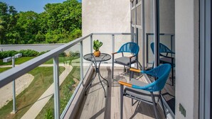 Un balcon avec une table et des chaises, une plante en pot et une vue sur un paysage verdoyant.