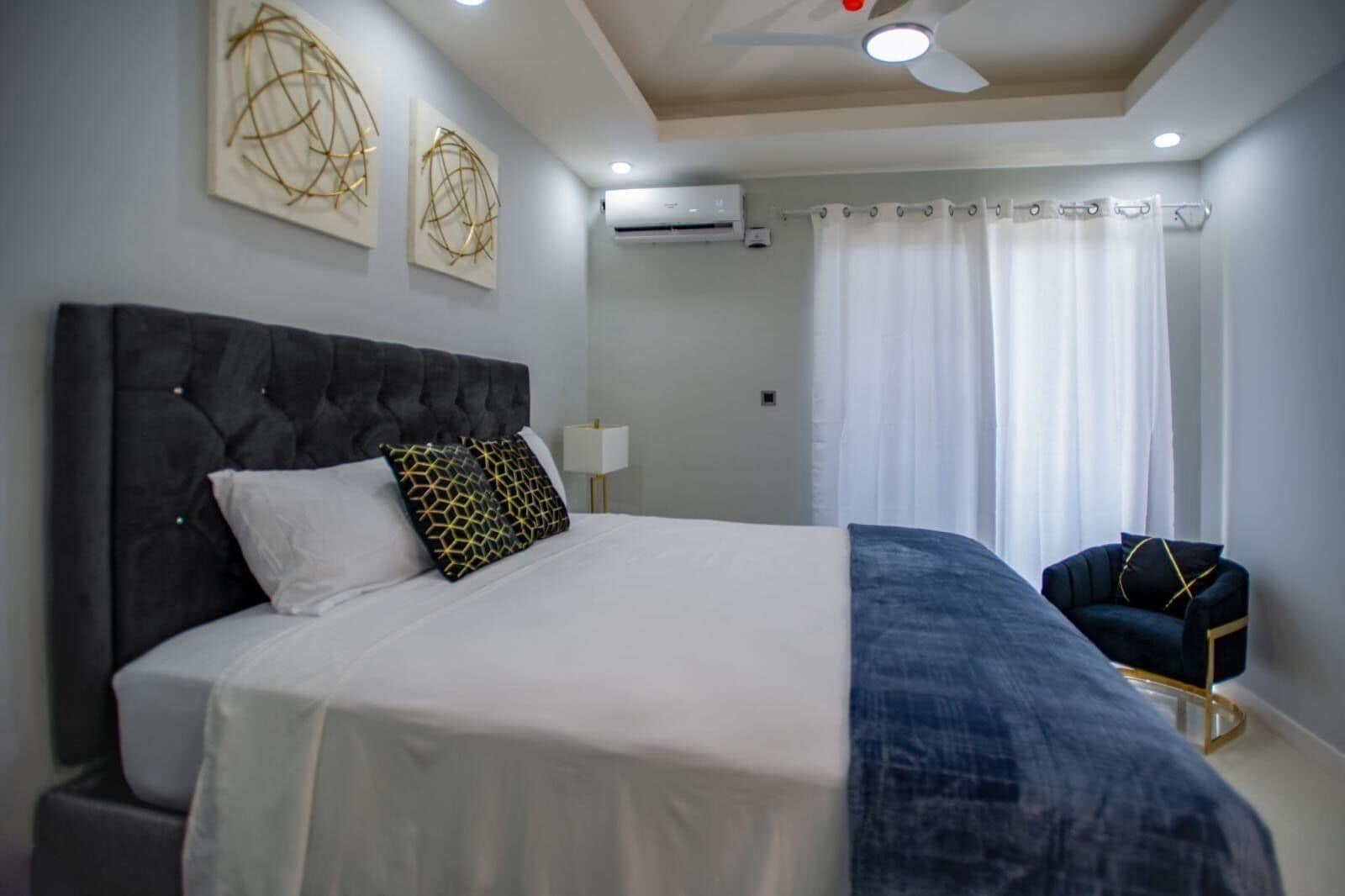 Un dormitorio moderno con una cama grande, un ventilador de techo y obras de arte en las paredes.