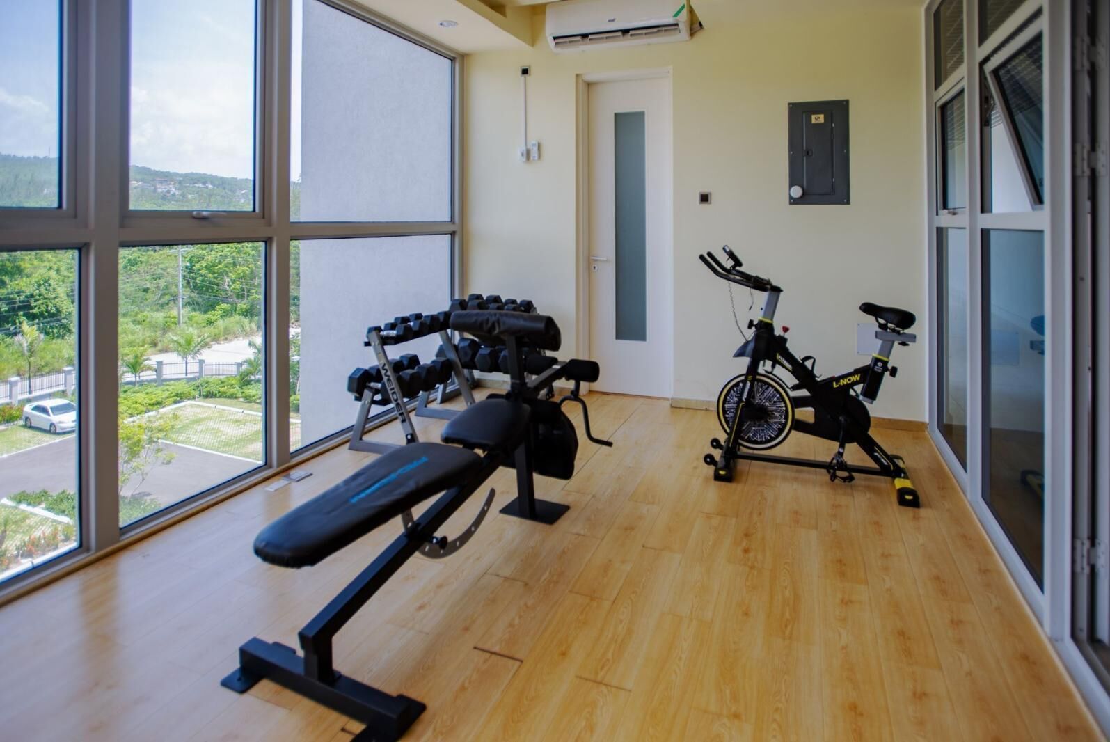 A gym with exercise equipment, large windows, and a view of the outside.