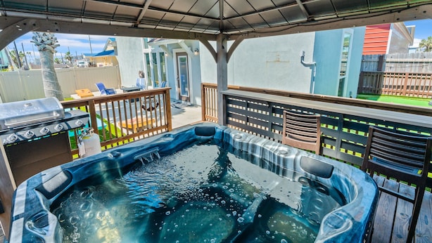 A hot tub under a pergola with a view of a backyard and a house. - Retreat Port Aransas | A Retreat DFW Experience (Port Aransas)