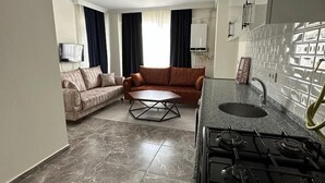 A compact living space with a kitchen area, a sofa, a coffee table, and a TV. - Trabzon White Life (Trabzon)