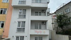 A multi-story residential building with balconies, air conditioning units, and a visible sign on the ground floor. - Trabzon White Life (Trabzon)