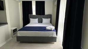 A modern hotel room with a large bed, a flat-screen TV, and a small bedside table. - Trabzon White Life (Trabzon)