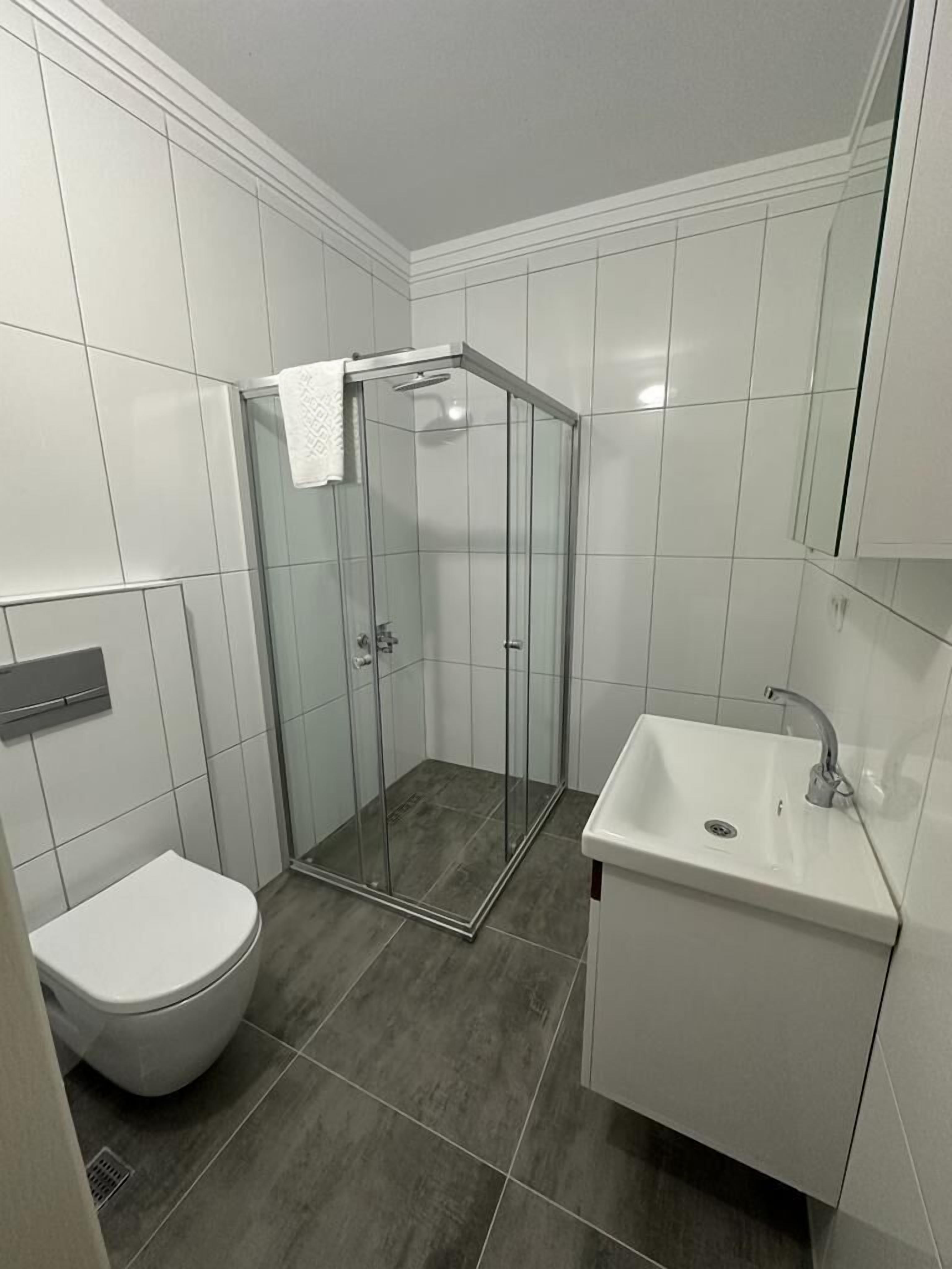 A bathroom with a glass-enclosed shower, a white sink, and a toilet.