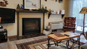 Una sala de estar acogedora con chimenea, televisor, alfombra estampada y un sillón cómodo.