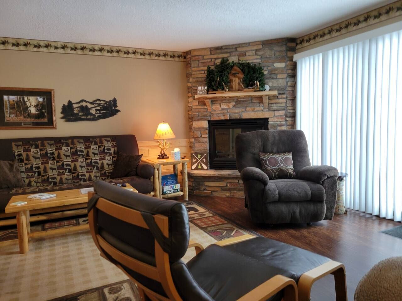 A cozy living room with a stone fireplace, a sofa, a chair, and a coffee table.