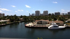 A marina with a yacht docked, surrounded by palm trees and a city skyline in the background. - golden isles # 509 Water view (Hallandale Beach)
