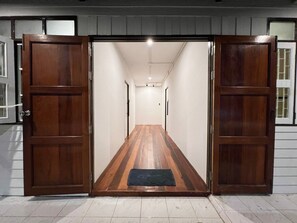 A hallway with wooden doors and a welcome mat at the entrance. - House Ju (Bangkok)