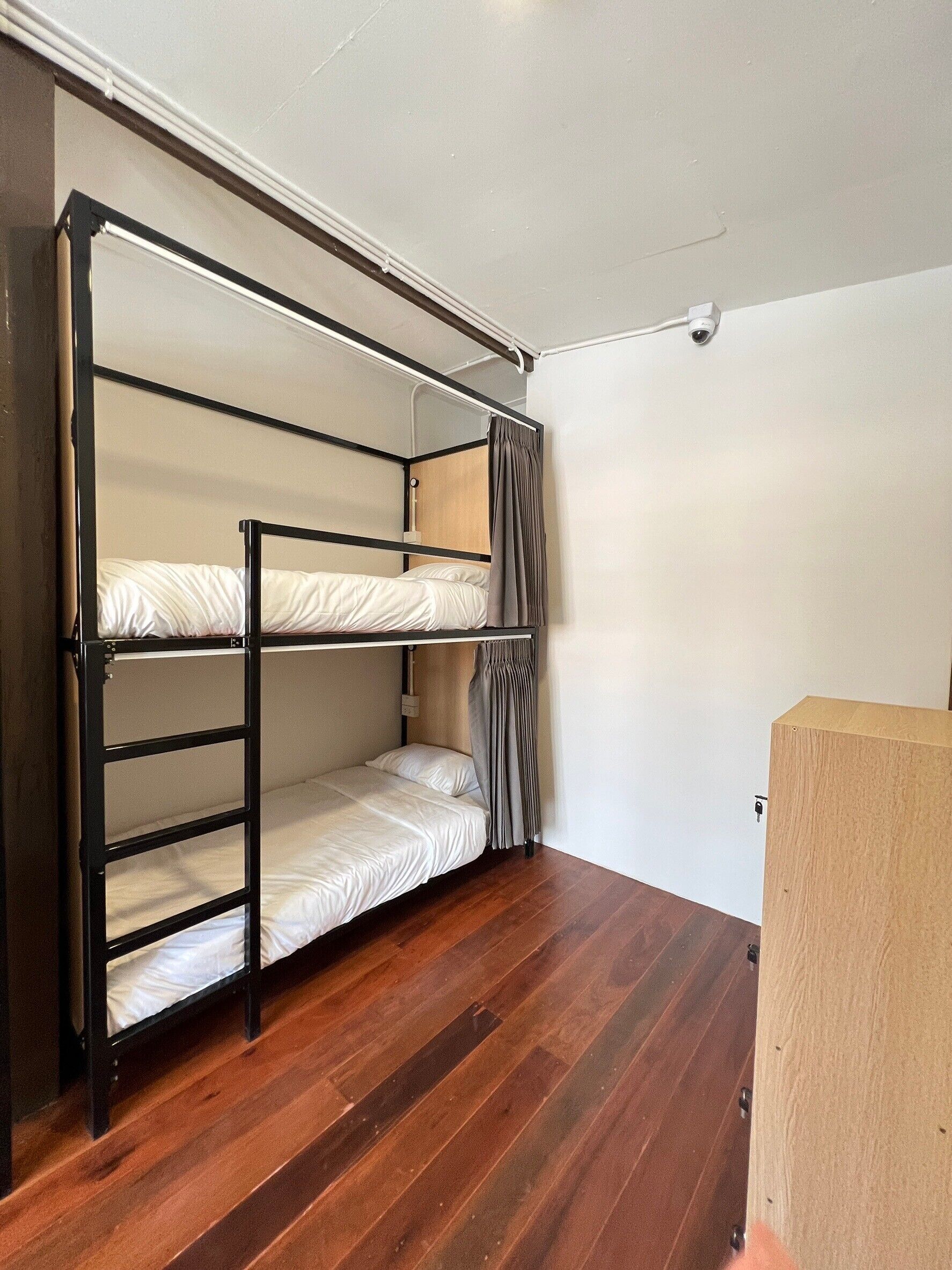 Una cama literera en una habitación con suelo de madera y paredes blancas.