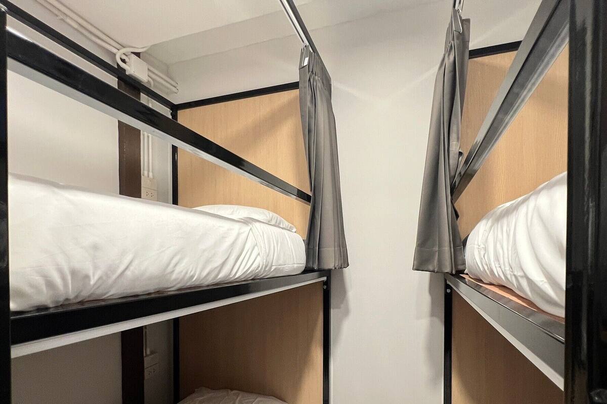 A compact room with bunk beds, wooden flooring, and a curtain on one side.
