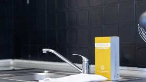 A kitchen with a modern design, featuring a black backsplash, stainless steel sink, and a yellow housekeeping kit on the counter. - Studio Les Vacances a Andernos (Andernos-les-Bains)