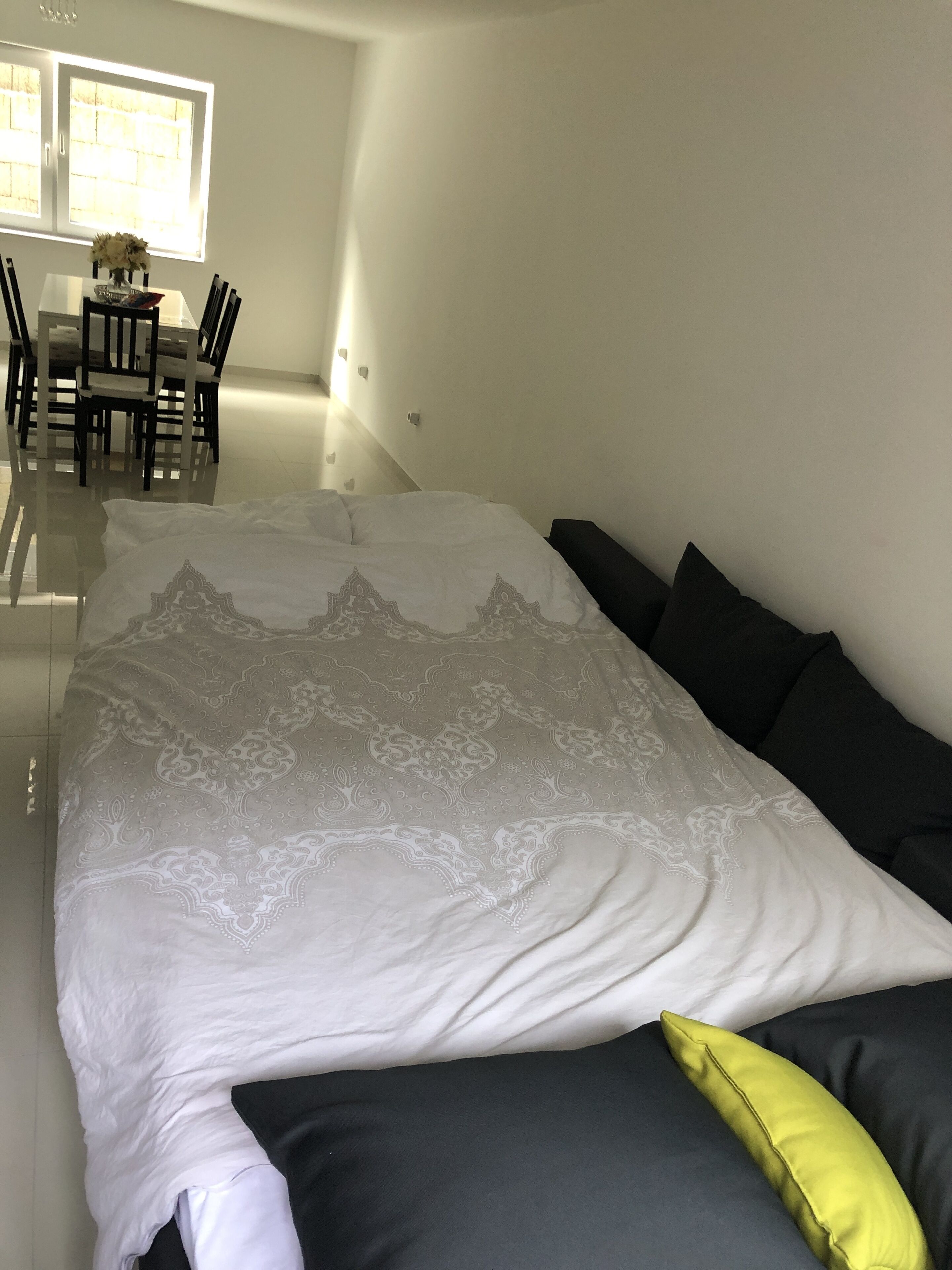 Un dormitorio con una cama grande, una mesa de comedor con sillas y un ventanal con luz natural.