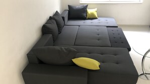 Ein modulares Sofa mit vielen Kissen und einem Glastisch.