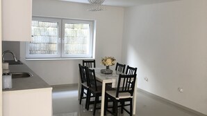 Eine moderne Küche mit Essbereich, ausgestattet mit einem großen Fenster, einer Chandelüster und einem gefliesten Boden.