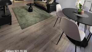 A modern living room with a black sofa, a round dining table, and a green rug. - Ajaccio Cosy & Charm (Ajaccio)