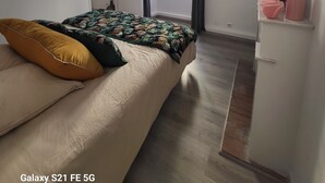 A bedroom with a bed, a dresser, a window with curtains, and an air conditioning unit. - Ajaccio Cosy & Charm (Ajaccio)