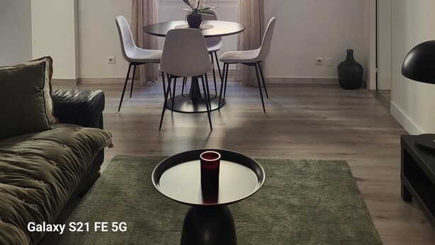 A modern living room with a round dining table, white chairs, a green sofa, and a Galaxy S21 FE 5G smartphone on a small table. - Ajaccio Cosy & Charm (Ajaccio)