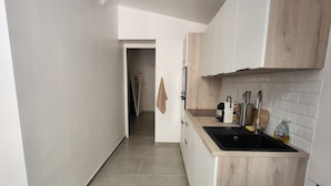 A modern kitchen with a built-in stove, white cabinets, and a tiled backsplash. - Ajaccio Cosy & Charm (Ajaccio)