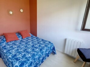 A bedroom with a bed, two pillows, a radiator, and a chair. - Apartment 500m from the sea, 4 sleeps, secure parking (Courseulles-sur-Mer)