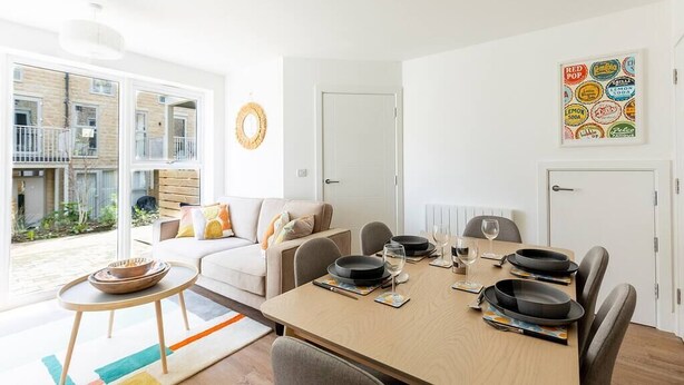 Una sala de estar moderna con comedor, un sofá, una mesa de centro y una mesa de comedor dispuesta con platos y vasos.