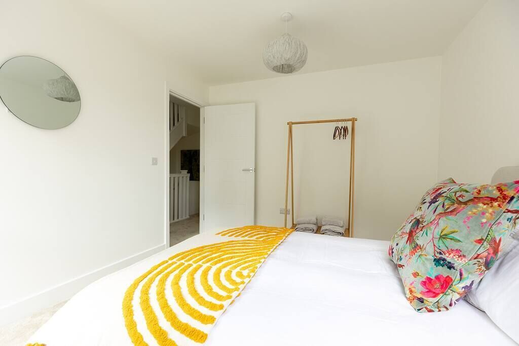 Un dormitorio con cama, lámpara colgante, puerta y espejo en la pared.