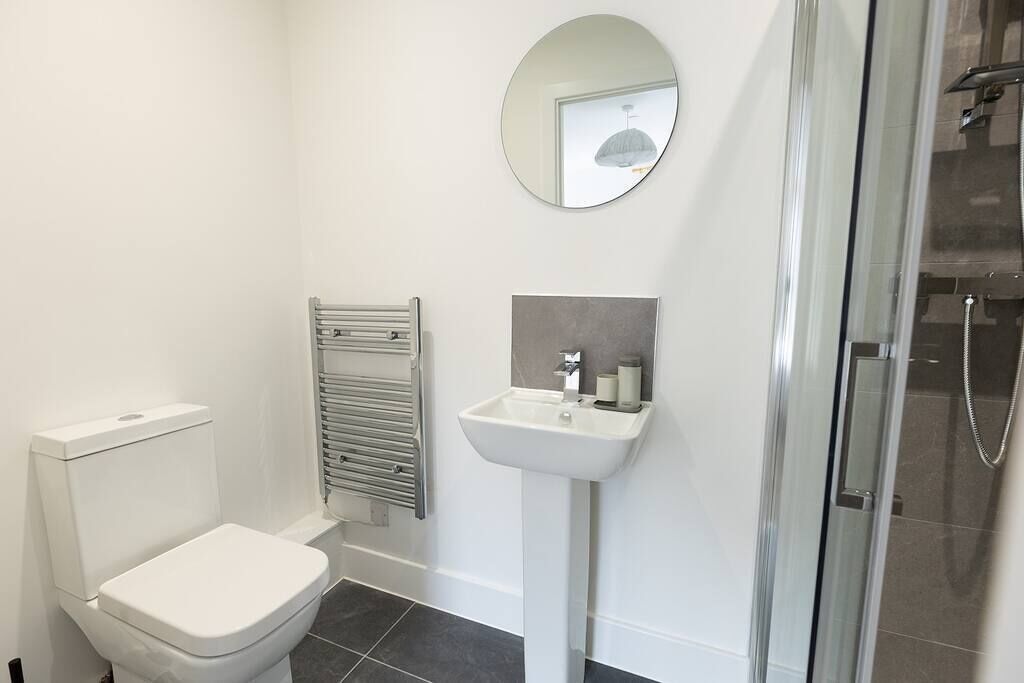 Une salle de bain moderne équipée de toilettes, d’un lavabo, d’un miroir et d’une douche.