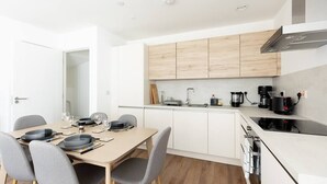 Una cocina moderna con armarios blancos, encimera de madera y una zona de comedor con una mesa preparada para cuatro.